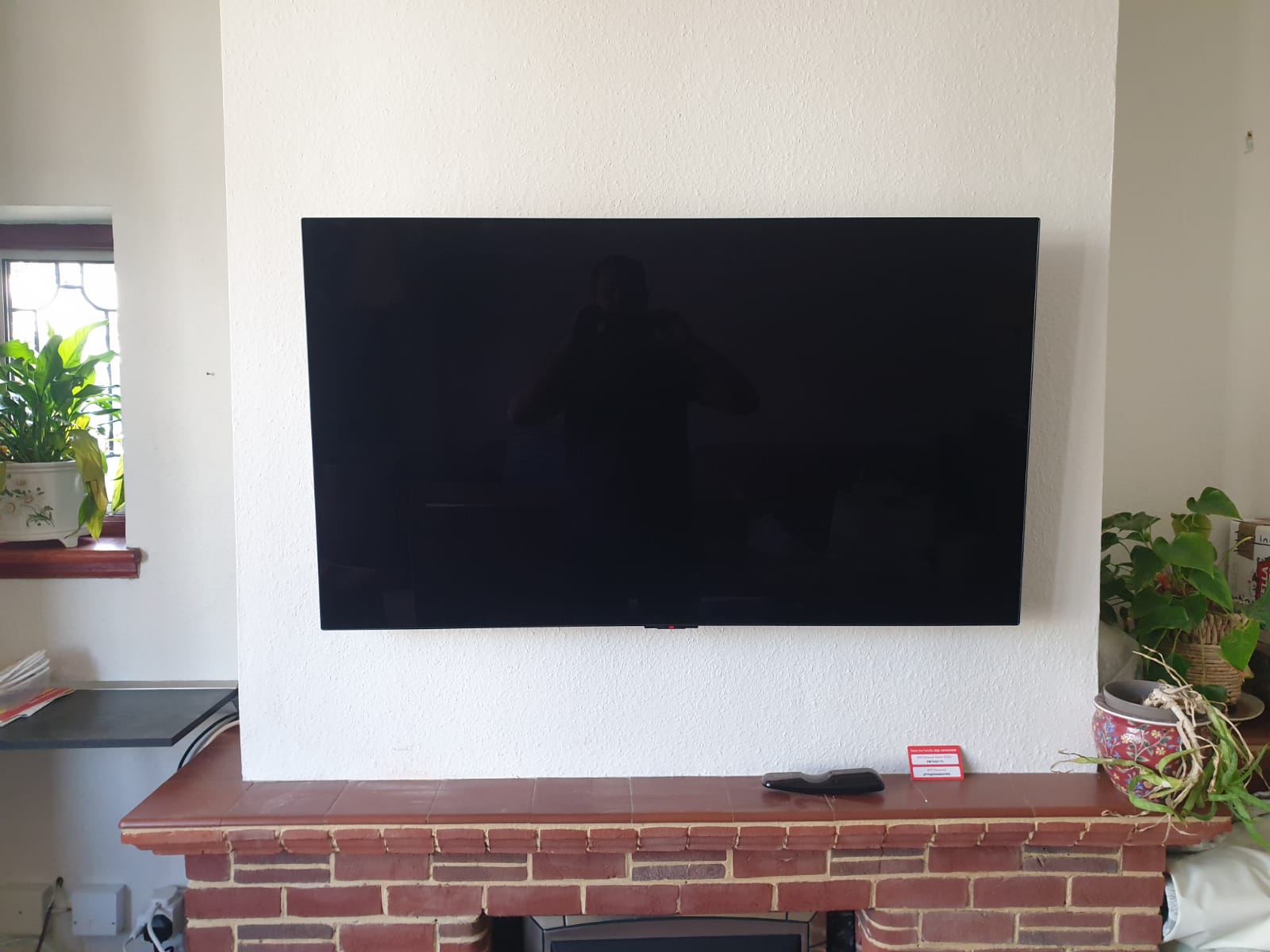 TV wall mounted onto chimney breast with cables going into chimney and coming out the side near the sockets.