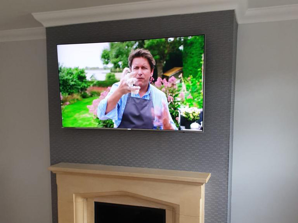 TV wall mounted on chimney with cables hidden and coming out the side near the sockets